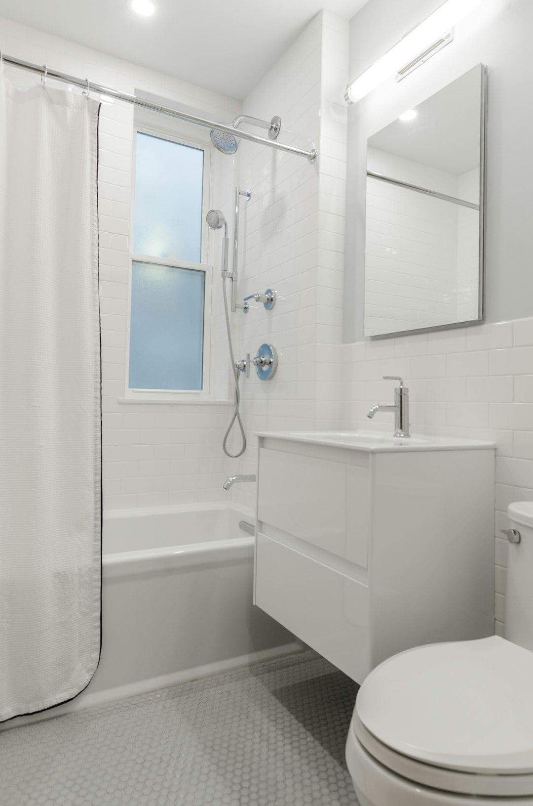 All white bathroom, white bathroom tiles, white subway tiles, chrome faucets, chrome shower head, chrome finishings, bathroom mirror, crystal door knob